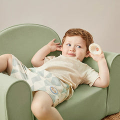 Child sitting on a green chair holding a small object