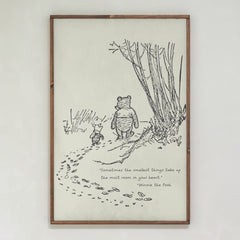 Framed illustration of Winnie the Pooh and Piglet with a quote on a white wall.