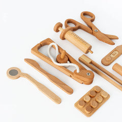 Set of wooden doctor tools including a thermometer, scissors, and stethoscope on a white background