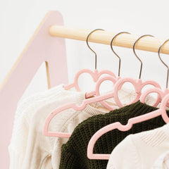 Pink heart-shaped hangers on a wooden rack with clothes.