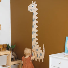 Child reaching up to a dinosaur-shaped growth chart on a brown wall.