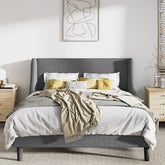 Gray upholstered bed with white bedding and yellow pillows in a bedroom setting.