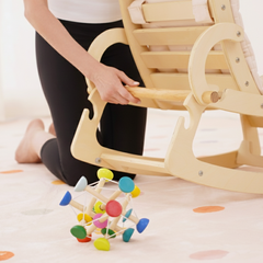 Child playing with a colorful wooden toy on a light-colored floor.