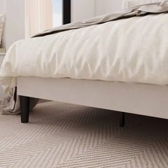 Close-up of a bed with white bedding on a textured carpet