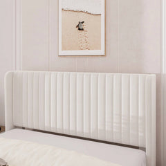 White upholstered headboard against a wall with framed artwork.