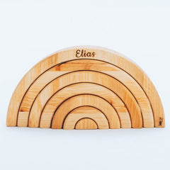 Wooden rainbow-shaped toy with 'Elias' engraved on a white background