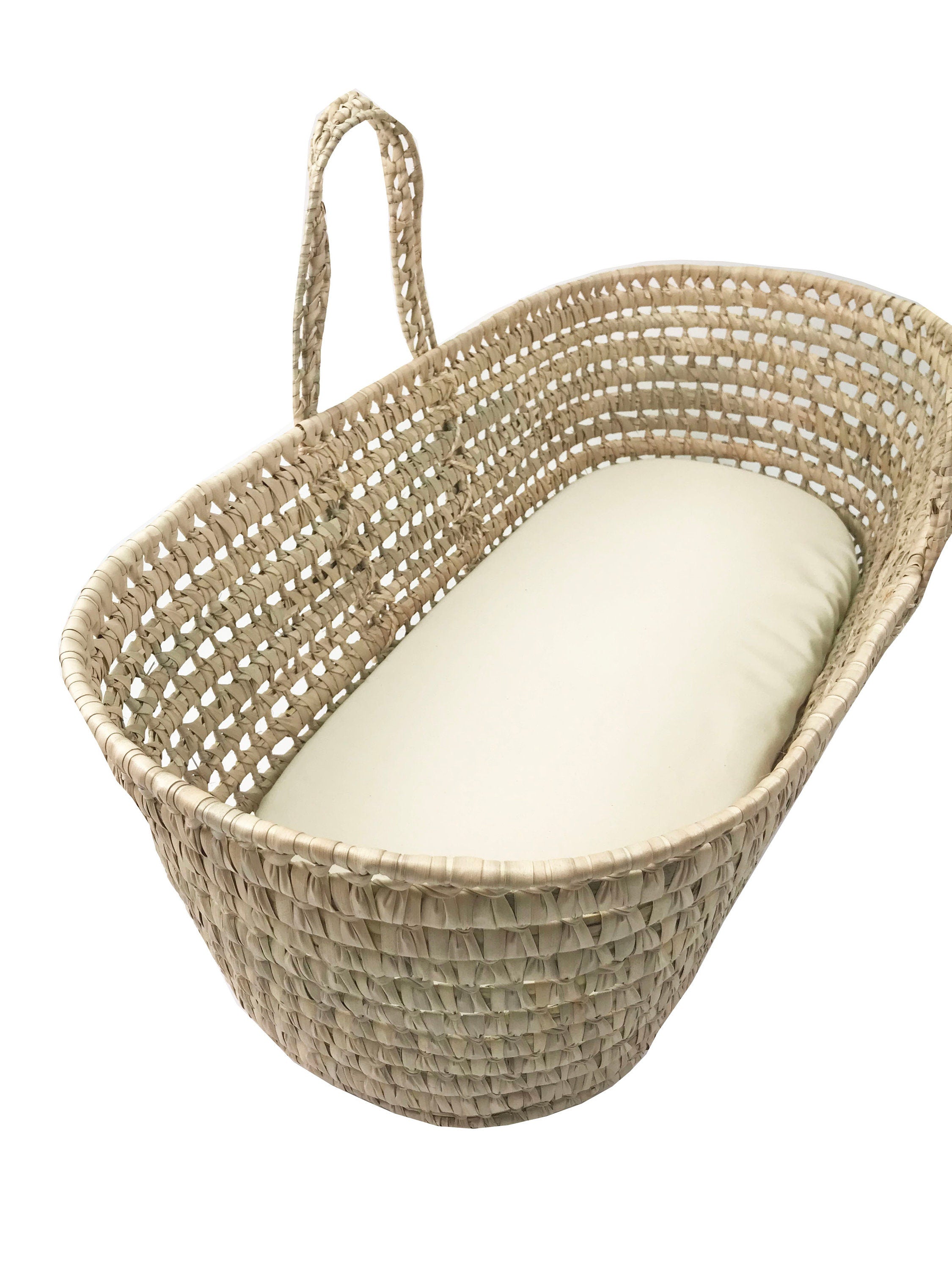 Wicker baby Moses basket with a white cushion on a white background