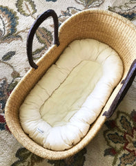 Wicker baby crib with white mattress on a patterned carpet