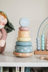 Stack of colorful wooden rings on a shelf with toys in the background