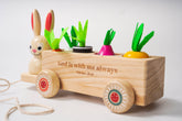 Wooden toy cart with rabbit figure and Easter vegetables, featuring the text 'God is with me always' on a light background.