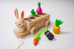 Wooden toy with rabbit figure, carrot, radish, and pineapple on a white background