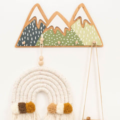 Decorative wall hanging with mountains and a rainbow on a white background
