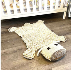 Organic wool sheep nursery rug on white background showing hand-knit texture and design