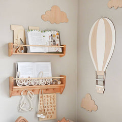 Wooden wall shelves with decorative items against a light gray wall with cloud and hot air balloon decorations.