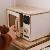 Wooden toy microwave with digital display and control knob, held by a hand.