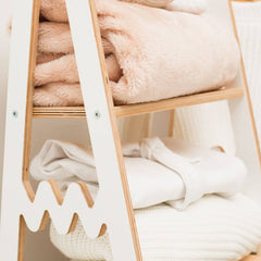 Wooden shelf with folded blankets in a neutral setting