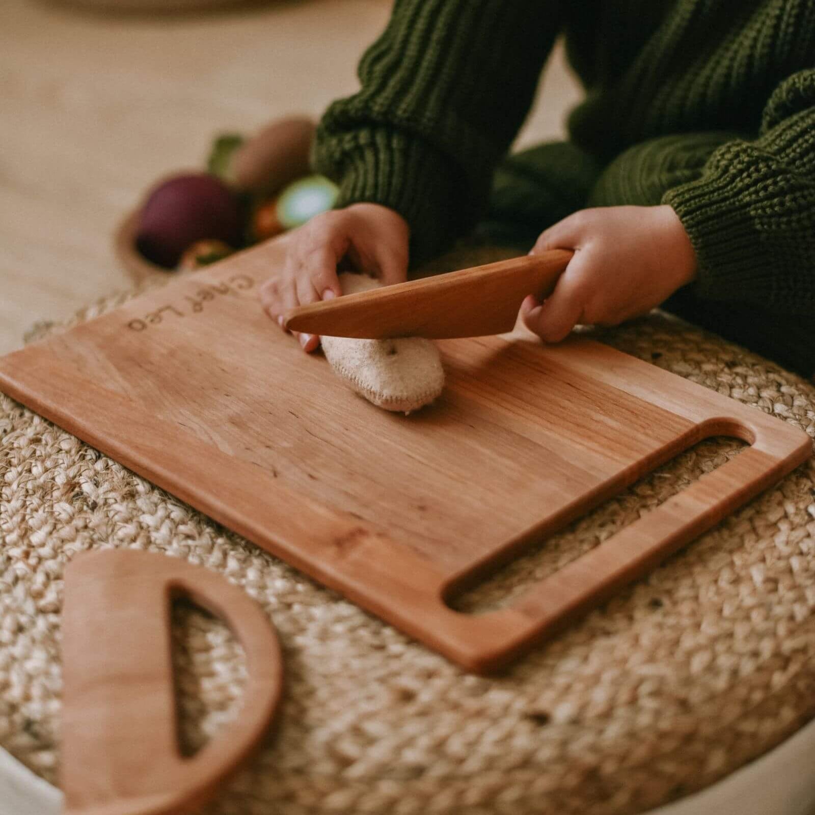 Person cutting a mushroom on a wooden cutting board with a green sweater.