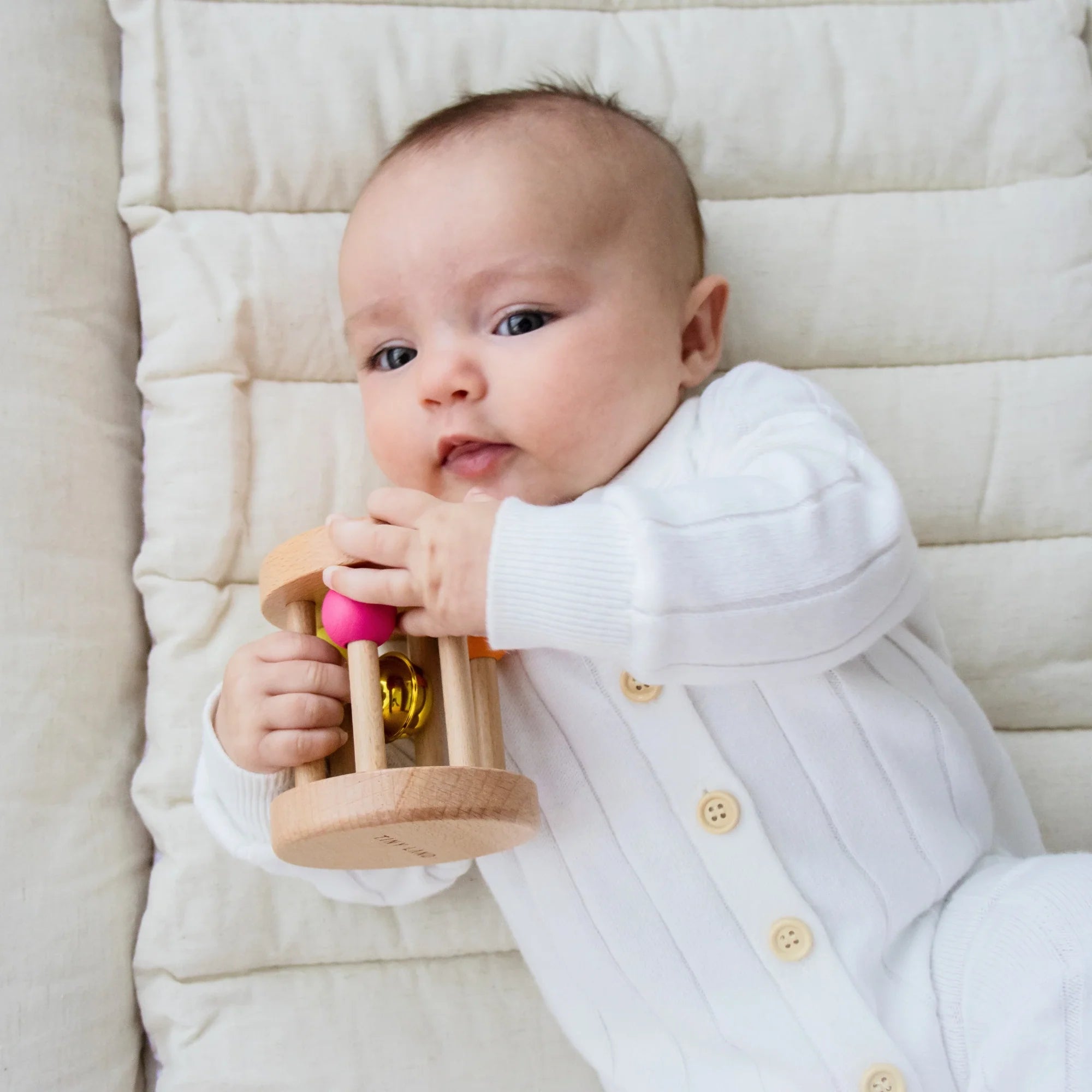 Close up of baby holding wooden rattle toy
