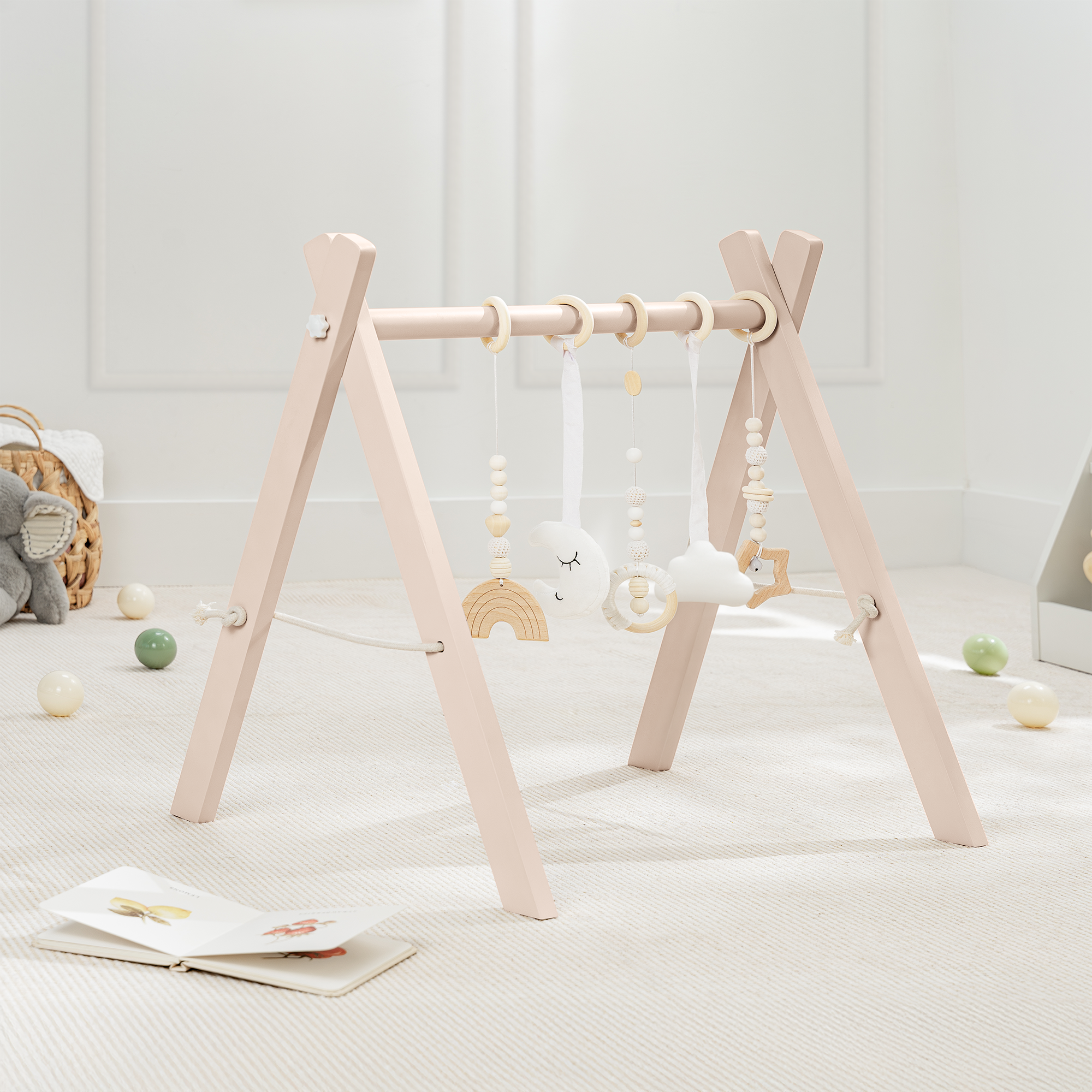 Wooden baby gym with hanging toys on a light wooden floor.