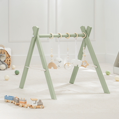 Children's play gym with hanging toys on a light wooden floor.