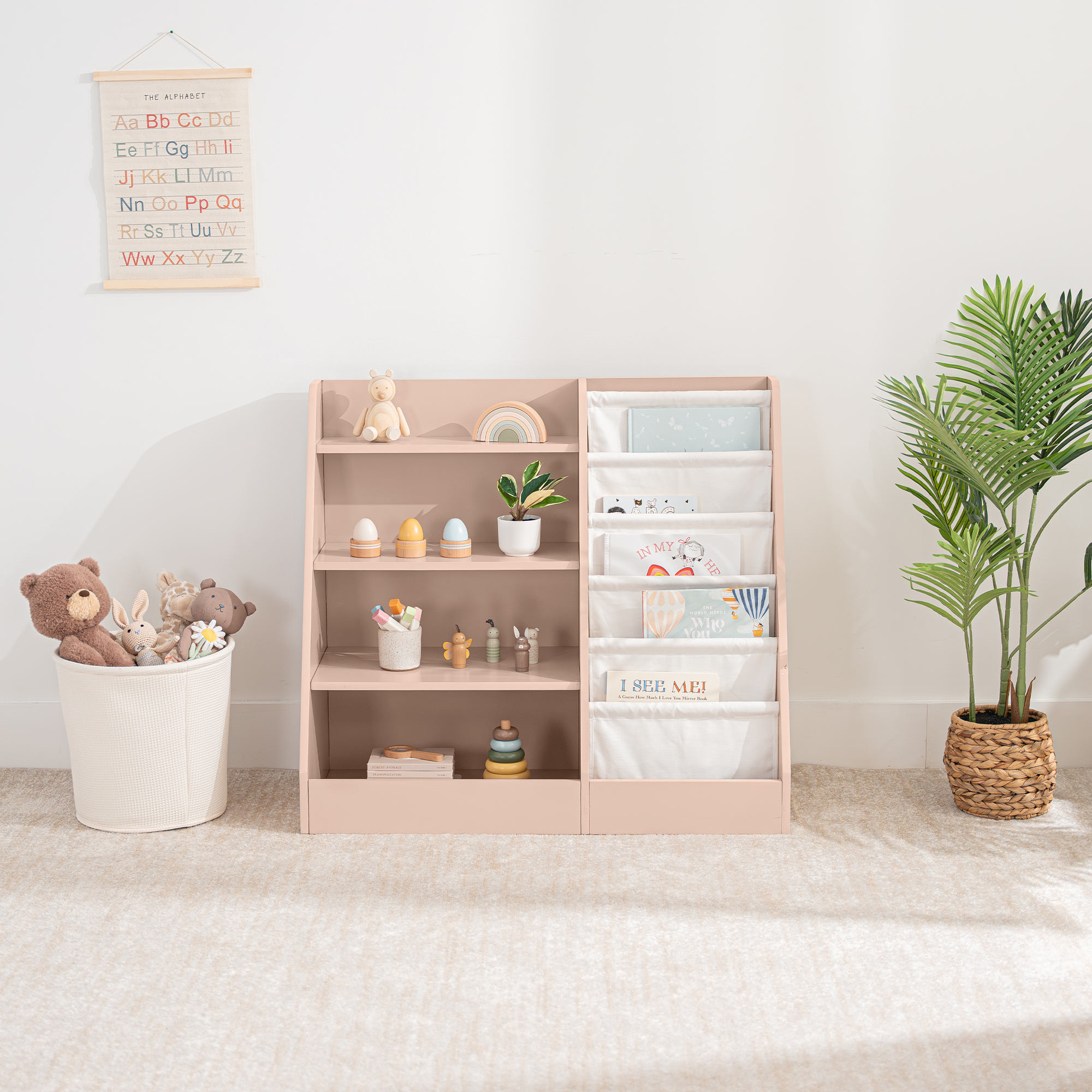 Blush kids bookshelf with open shelving and fabric compartments for books and toys in a nursery