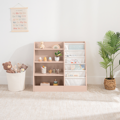 Blush kids bookshelf with open shelving and fabric compartments for books and toys in a nursery