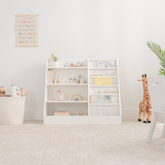 White kids bookshelf with open shelving and fabric compartments for books and toys in a playroom