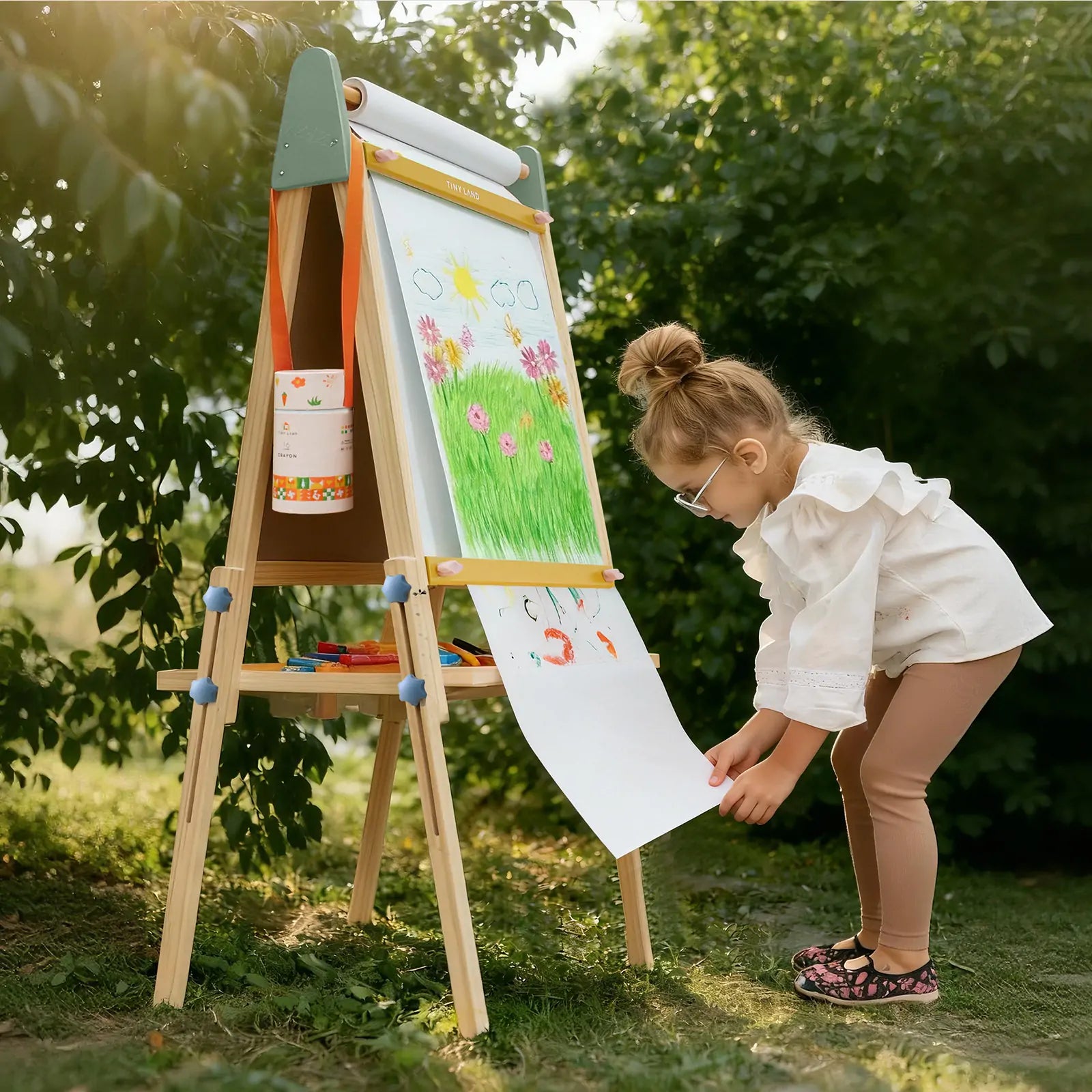 Child rolling out paper from the Tiny Land 3-in-1 wooden kids art easel