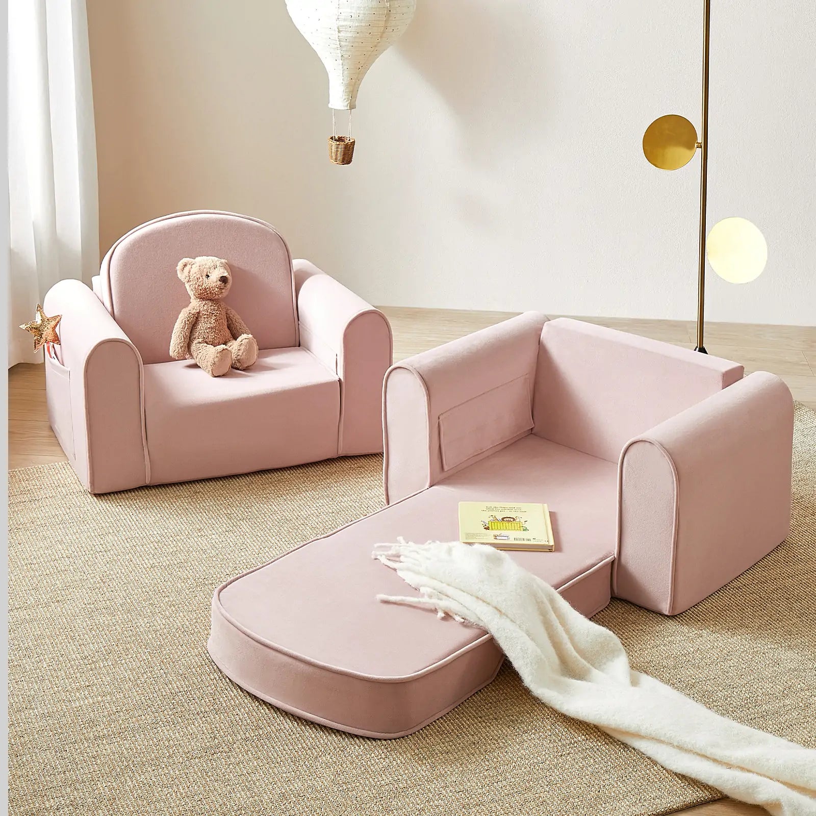 Pink children's chair and ottoman set with a teddy bear and blanket in a room.
