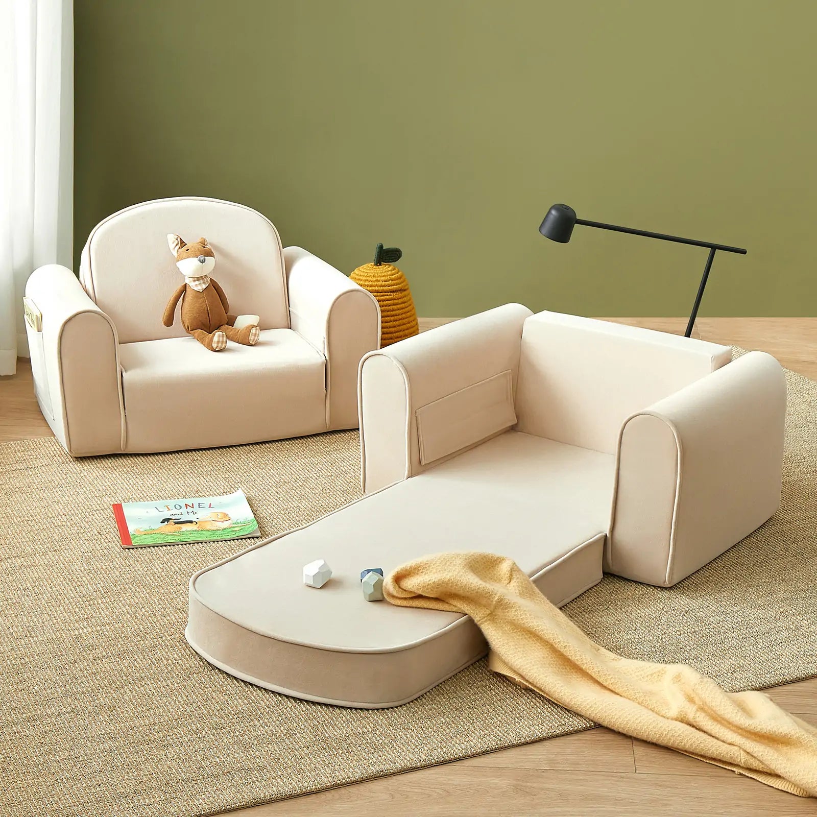 Children's beige sofa set with toys and a book on a wooden floor against a green wall.