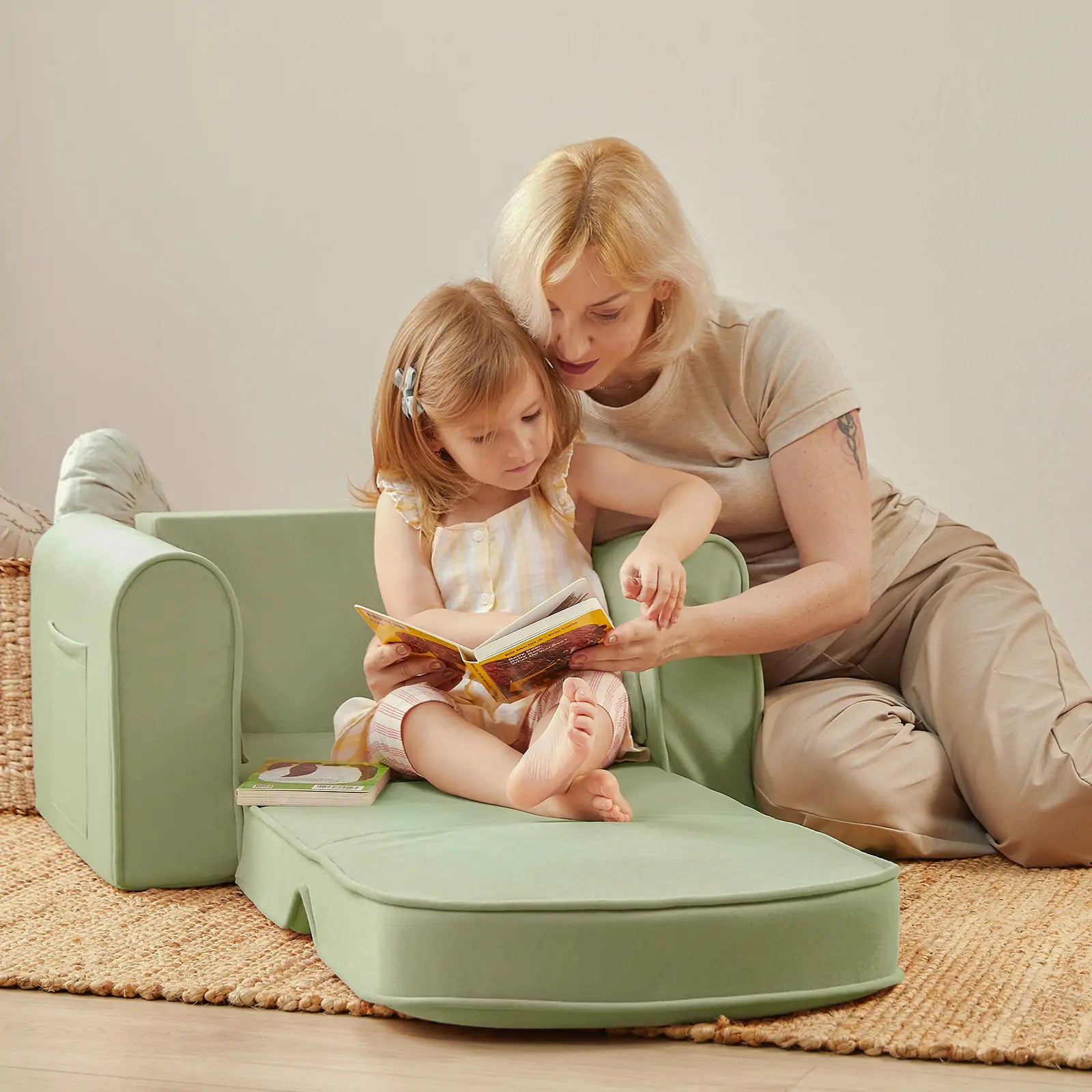 Woman and child sitting on a green children's chair reading a book together.