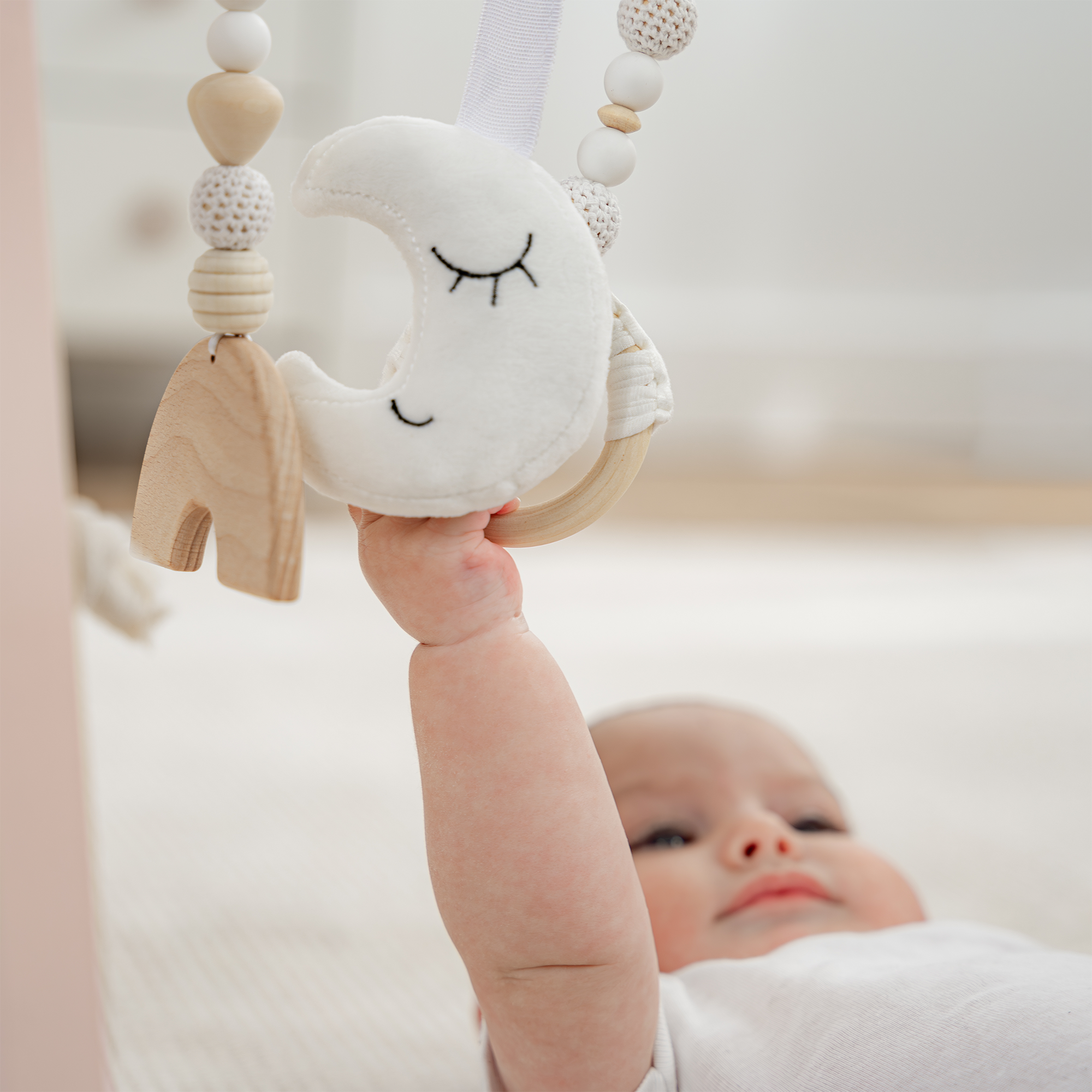 Baby holding a cloud-shaped toy with wooden elements