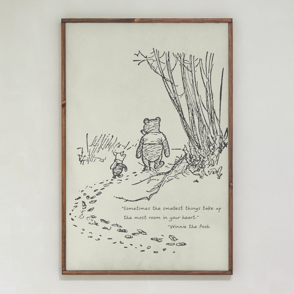 Framed illustration of Winnie the Pooh and Piglet with a quote on a white wall.