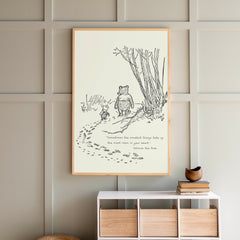 Framed illustration of a bear and a rabbit on a wall above a white console table with wooden drawers.
