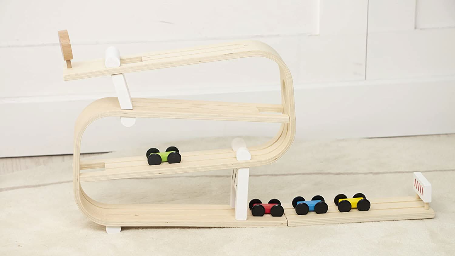 Wooden shelf with colorful dumbbells on a light wooden floor.