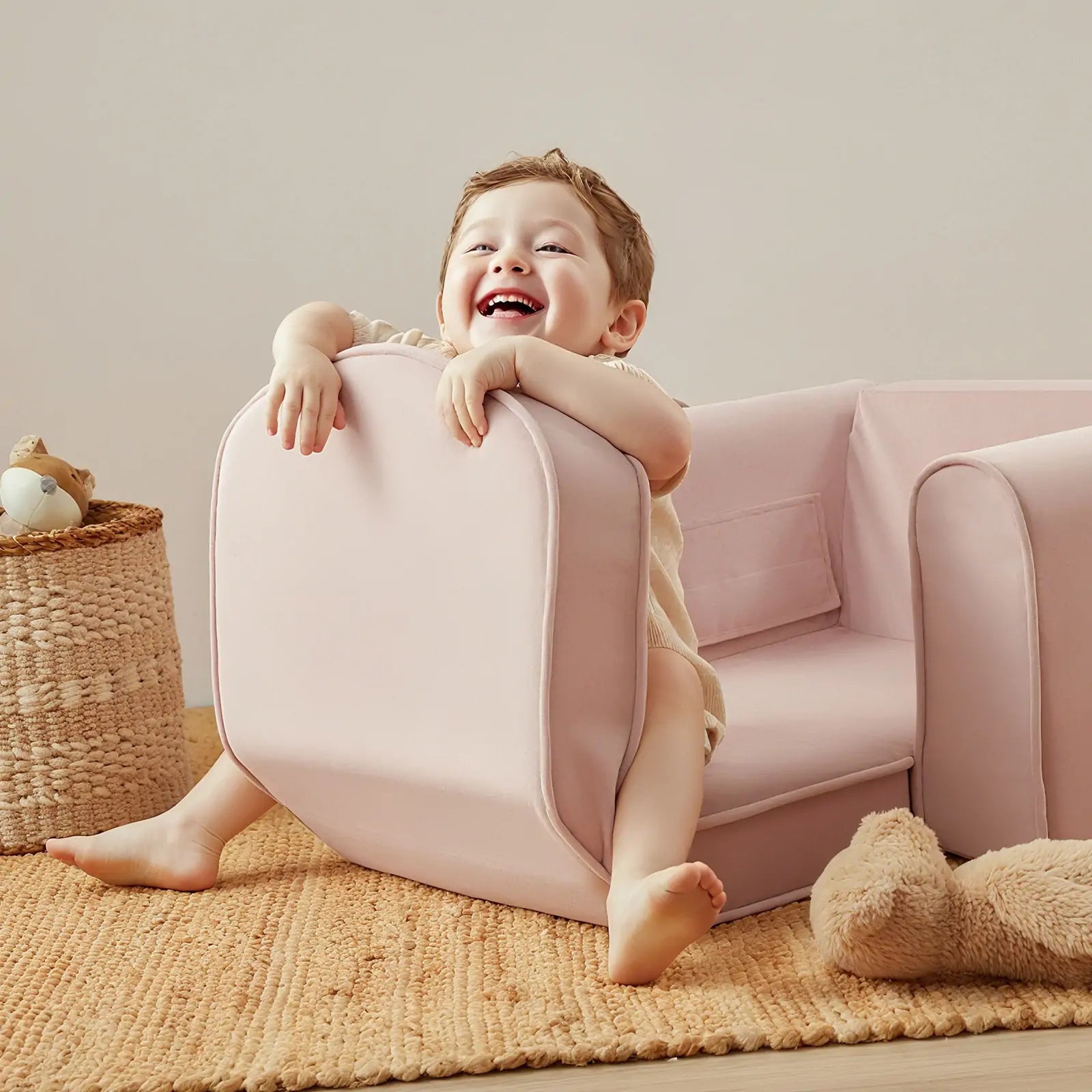 Child playing with a pink chair in a room with a couch and basket.
