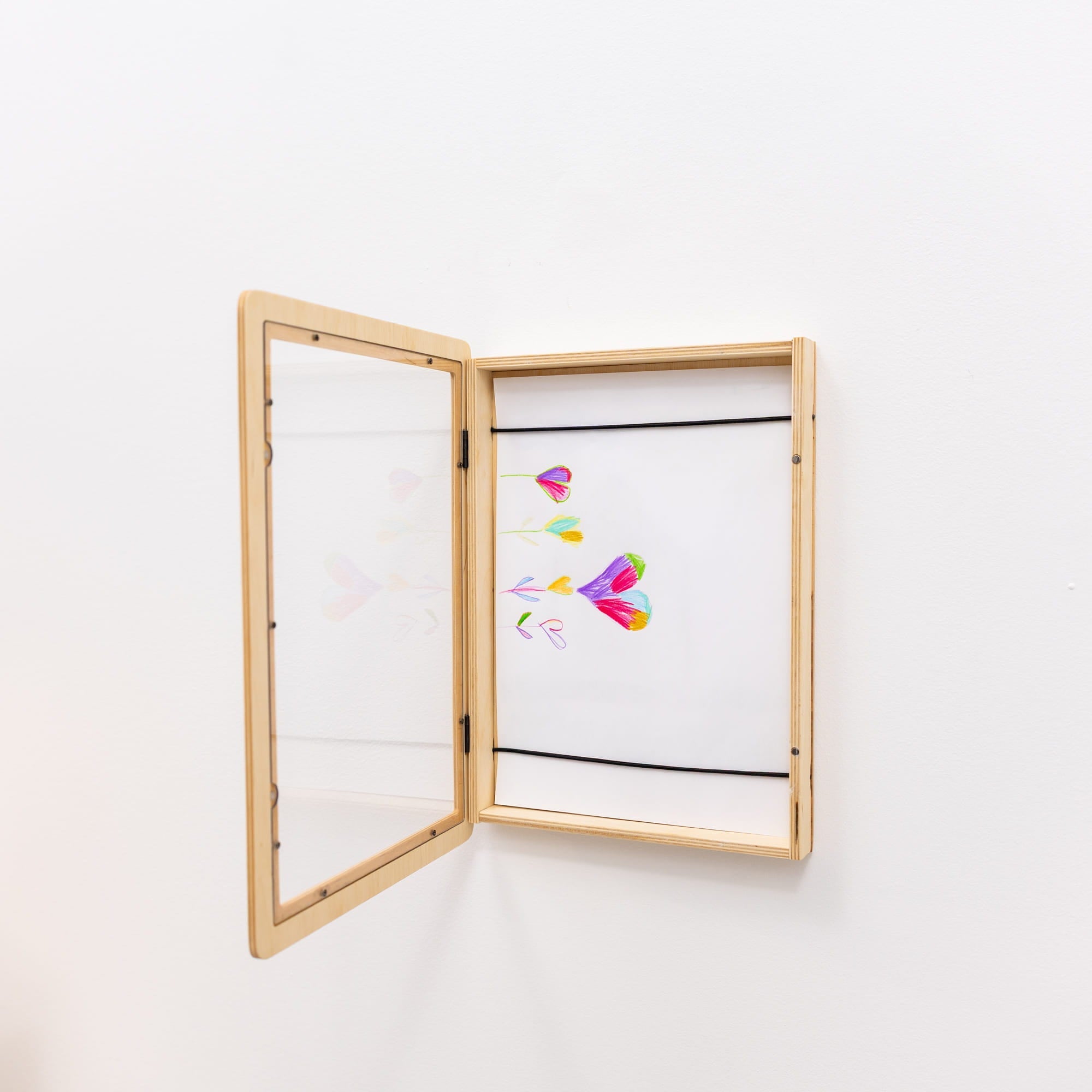 Open wooden frame displaying colorful abstract art on a white wall