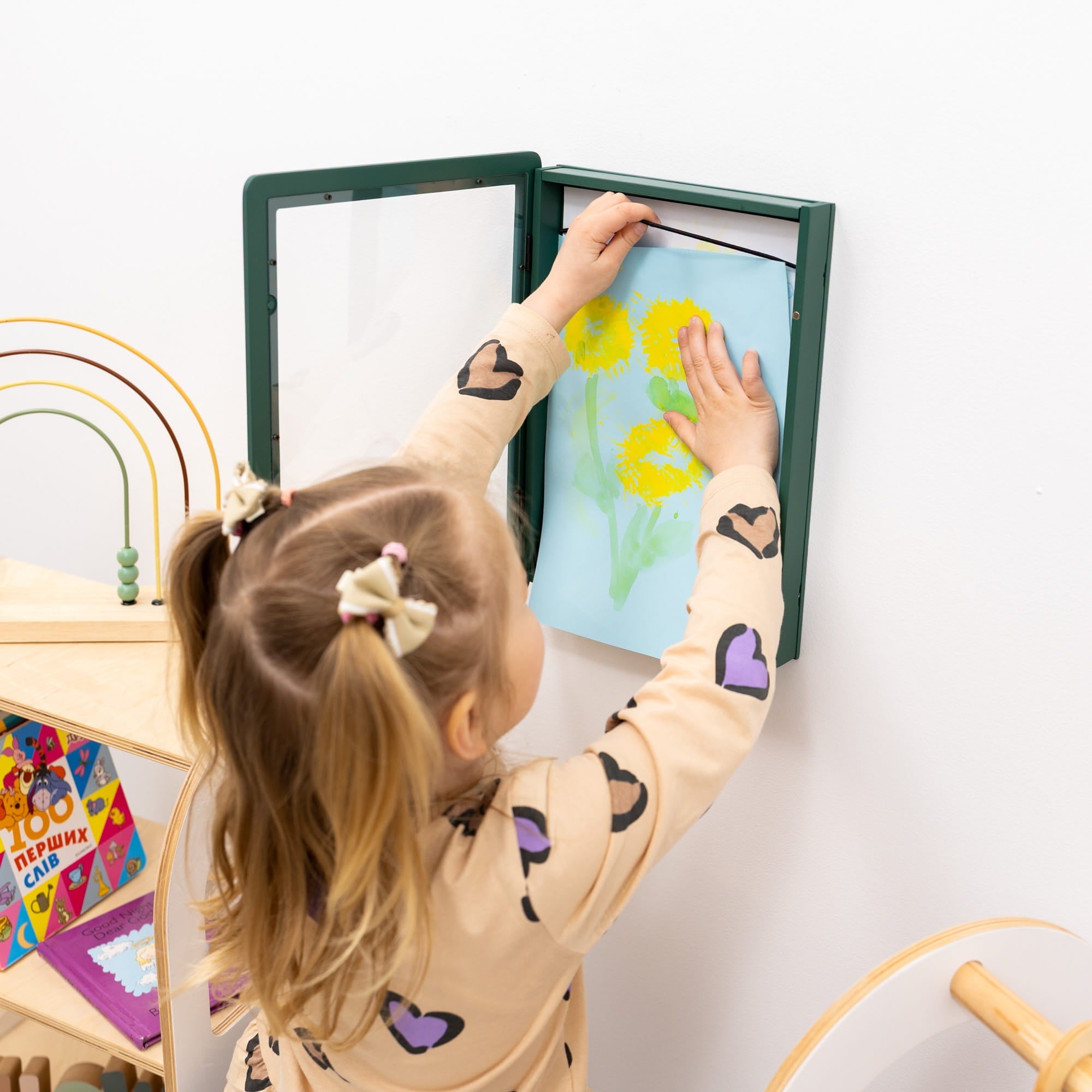 Child interacting with a children's educational toy on a white wall