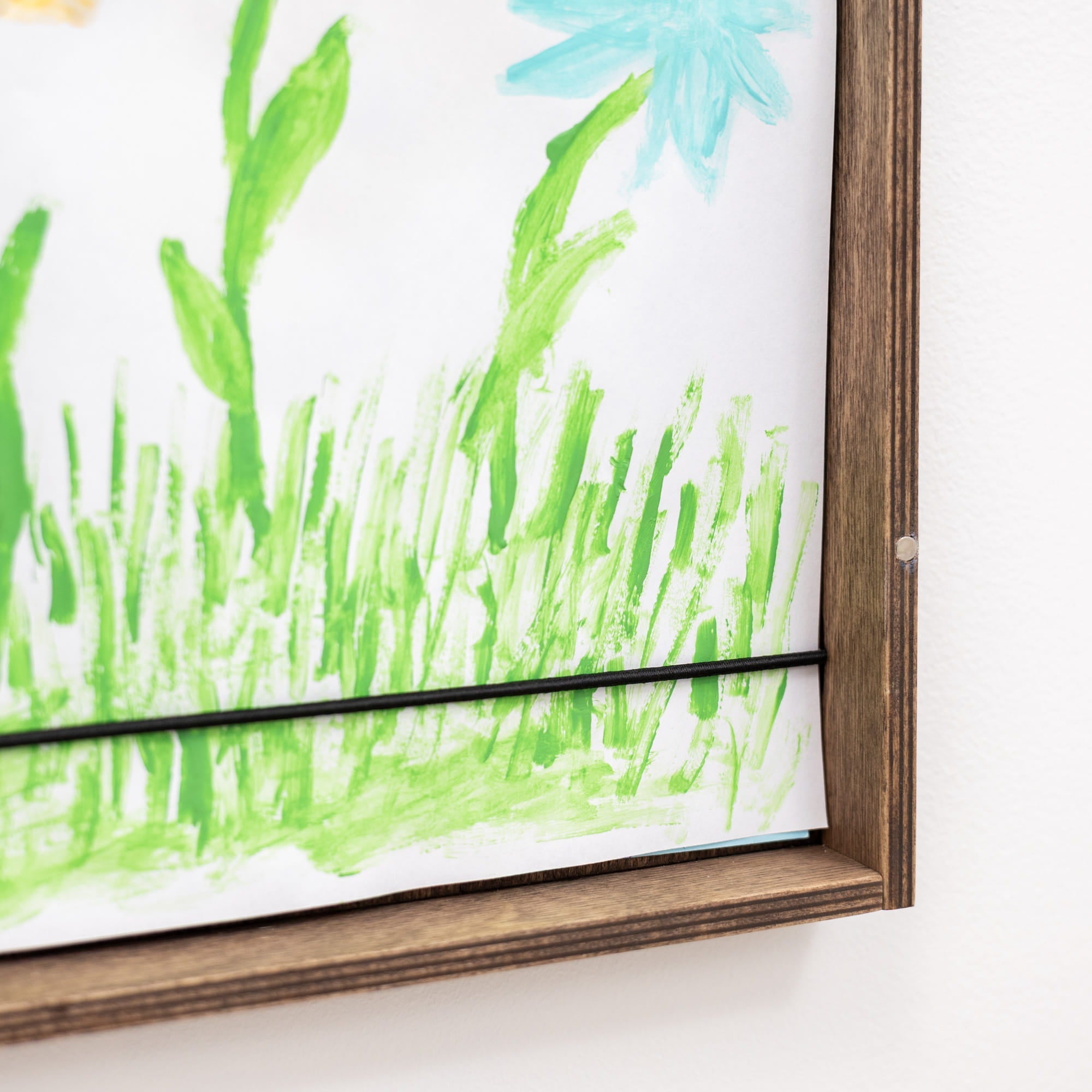 Framed artwork with green grass and blue flowers on a white background