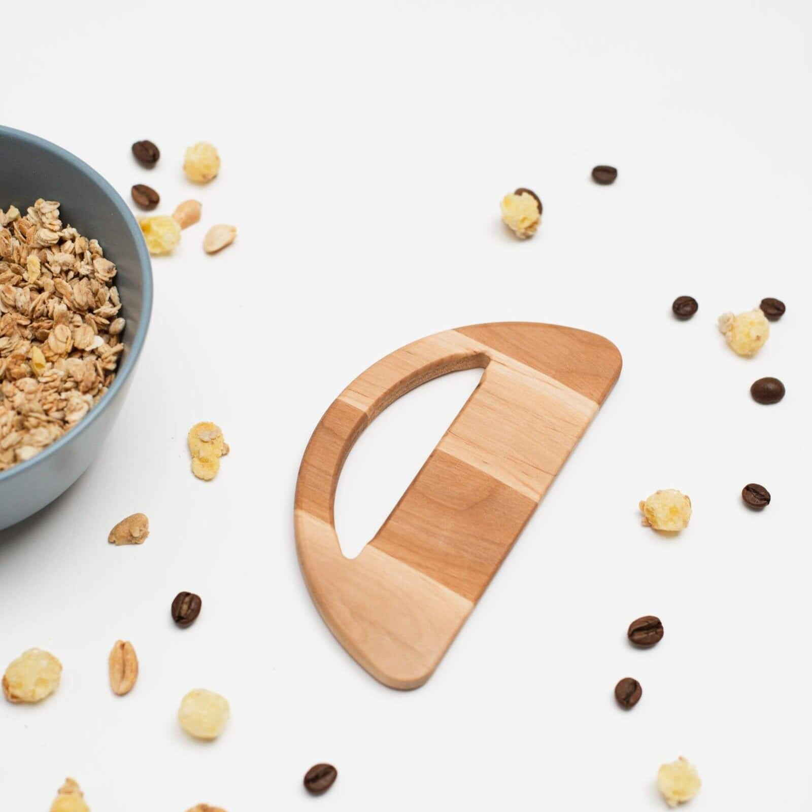 Wooden cereal scoop with granola and cereal pieces on a white background