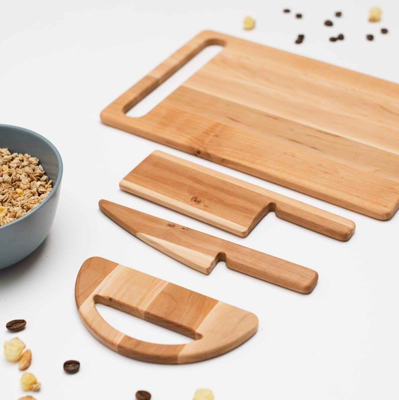 Set of wooden cutting boards and knives on a white surface with scattered ingredients.