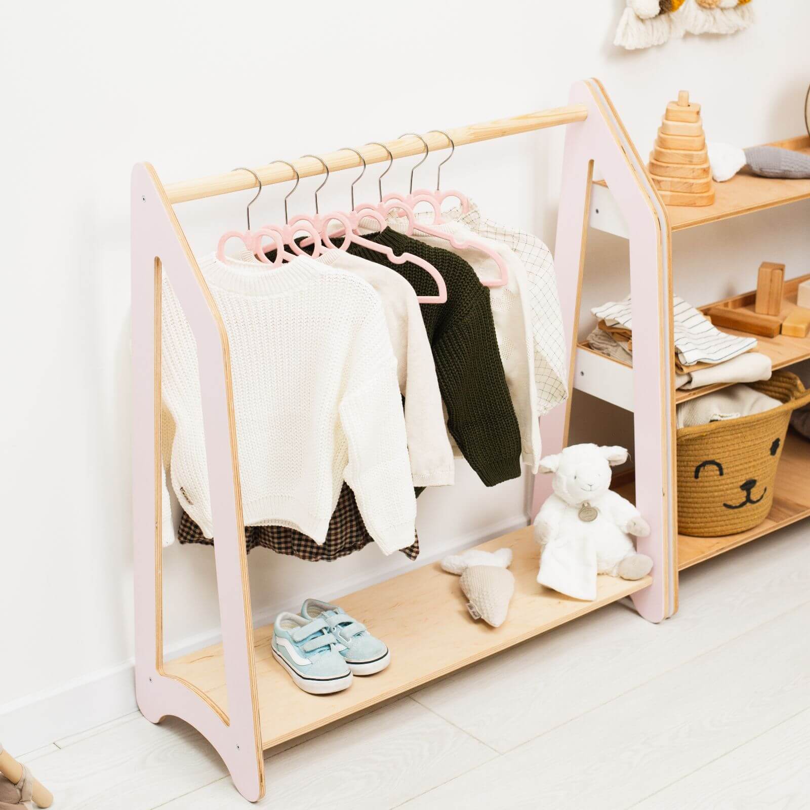 Children's clothing rack with clothes, shoes, and toys in a room setting.