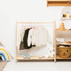 Children's clothing rack with clothes, shoes, and toys in a room setting.