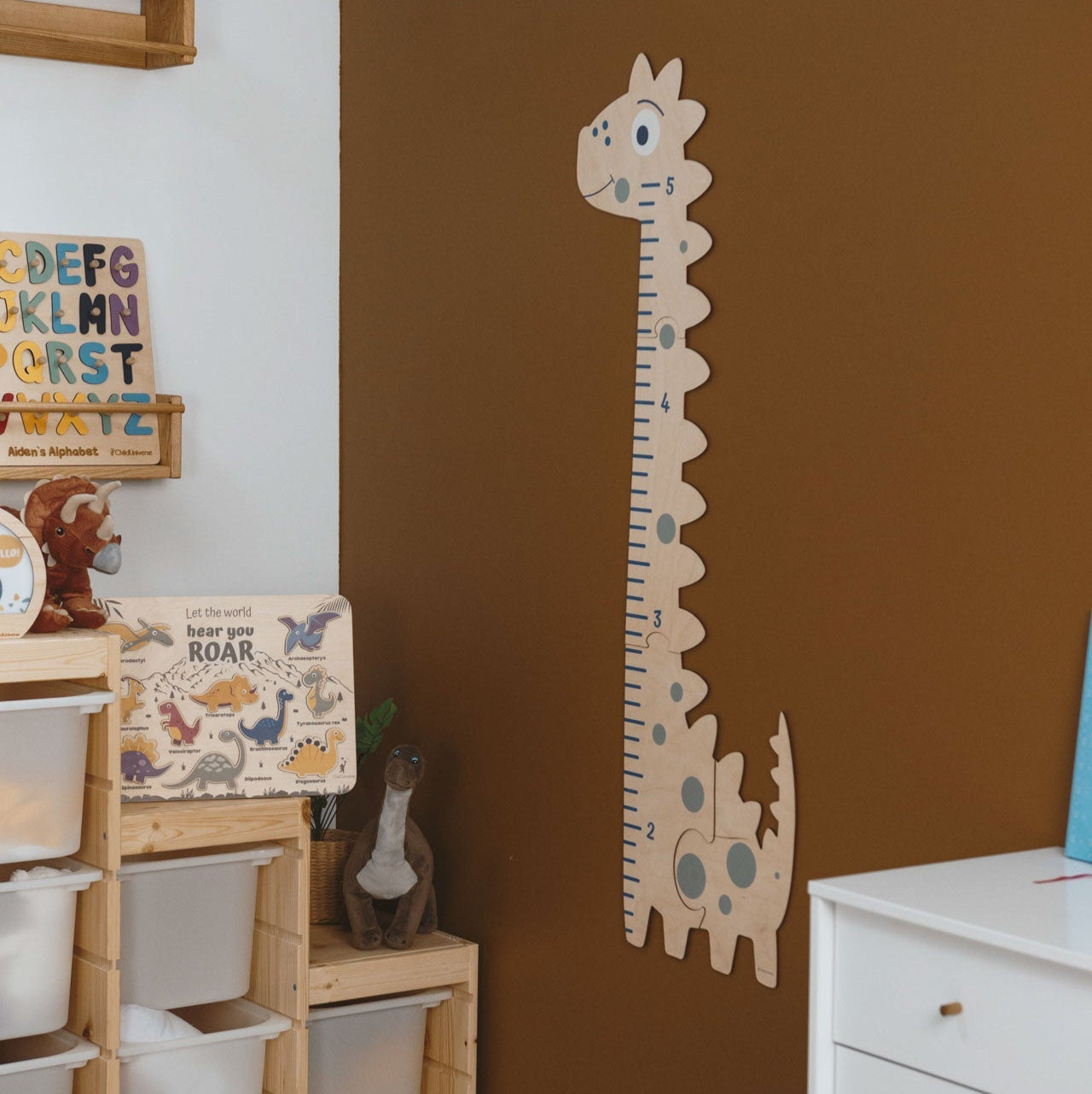 Giraffe-shaped growth chart on a brown wall in a child's room with shelves and decor.