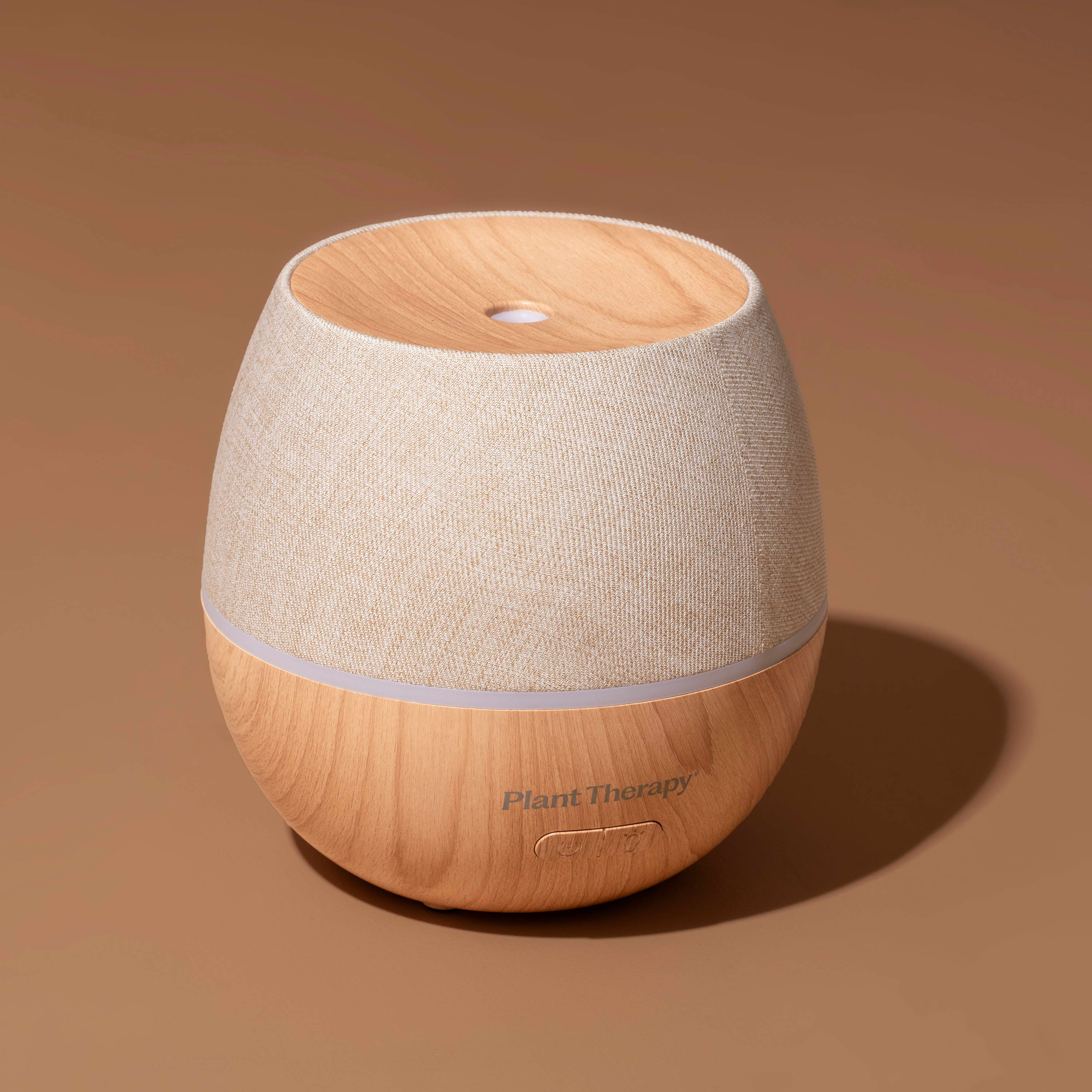 Wooden diffuser with beige fabric top on a brown background