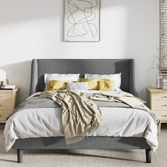 Gray upholstered bed with white bedding and yellow pillows in a bedroom setting.