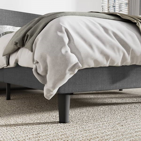 Gray bed with white bedding and a gray blanket in a bedroom setting