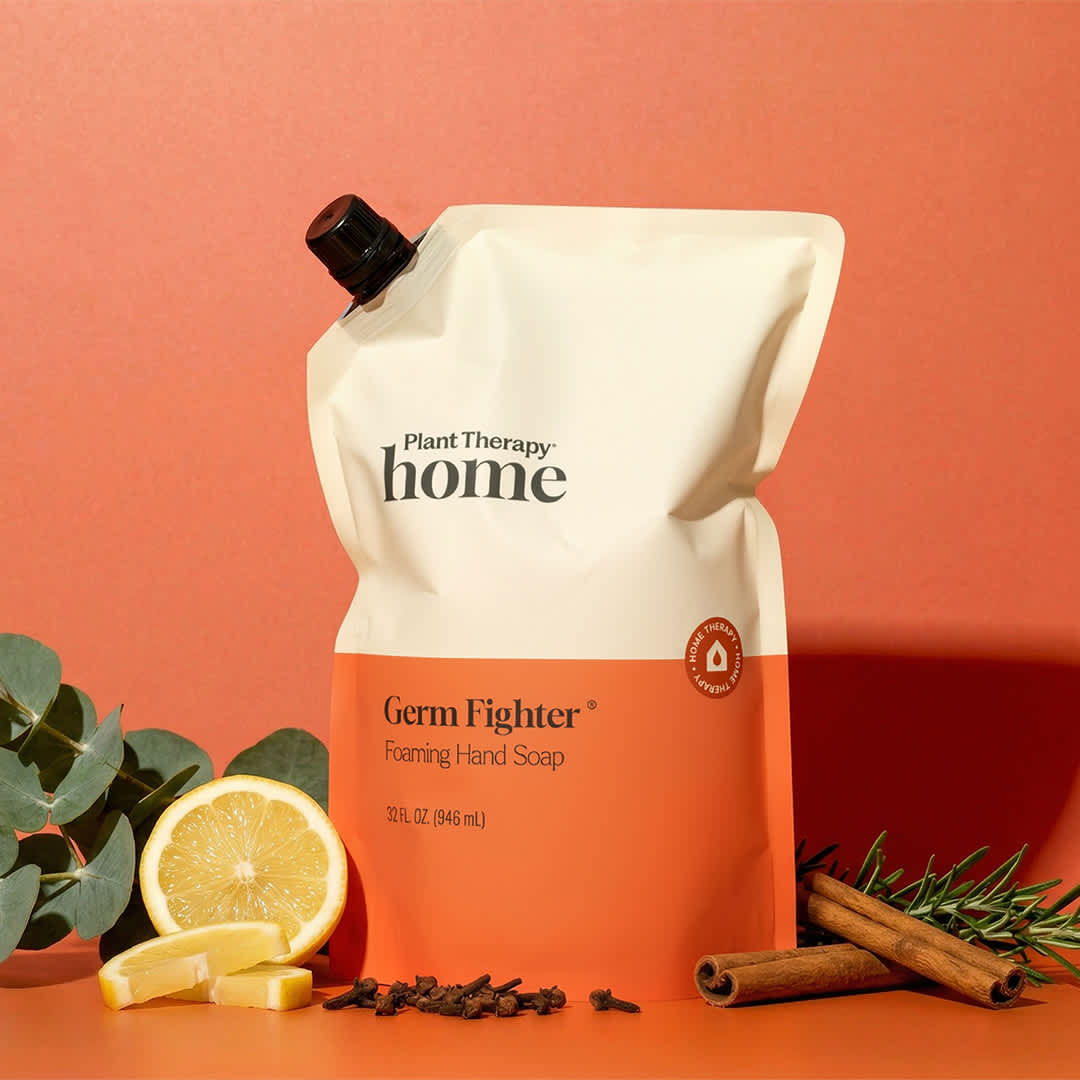 Plant Therapy home Germ Fighter Foaming Hand Soap packaging on an orange background with lemon and cinnamon.