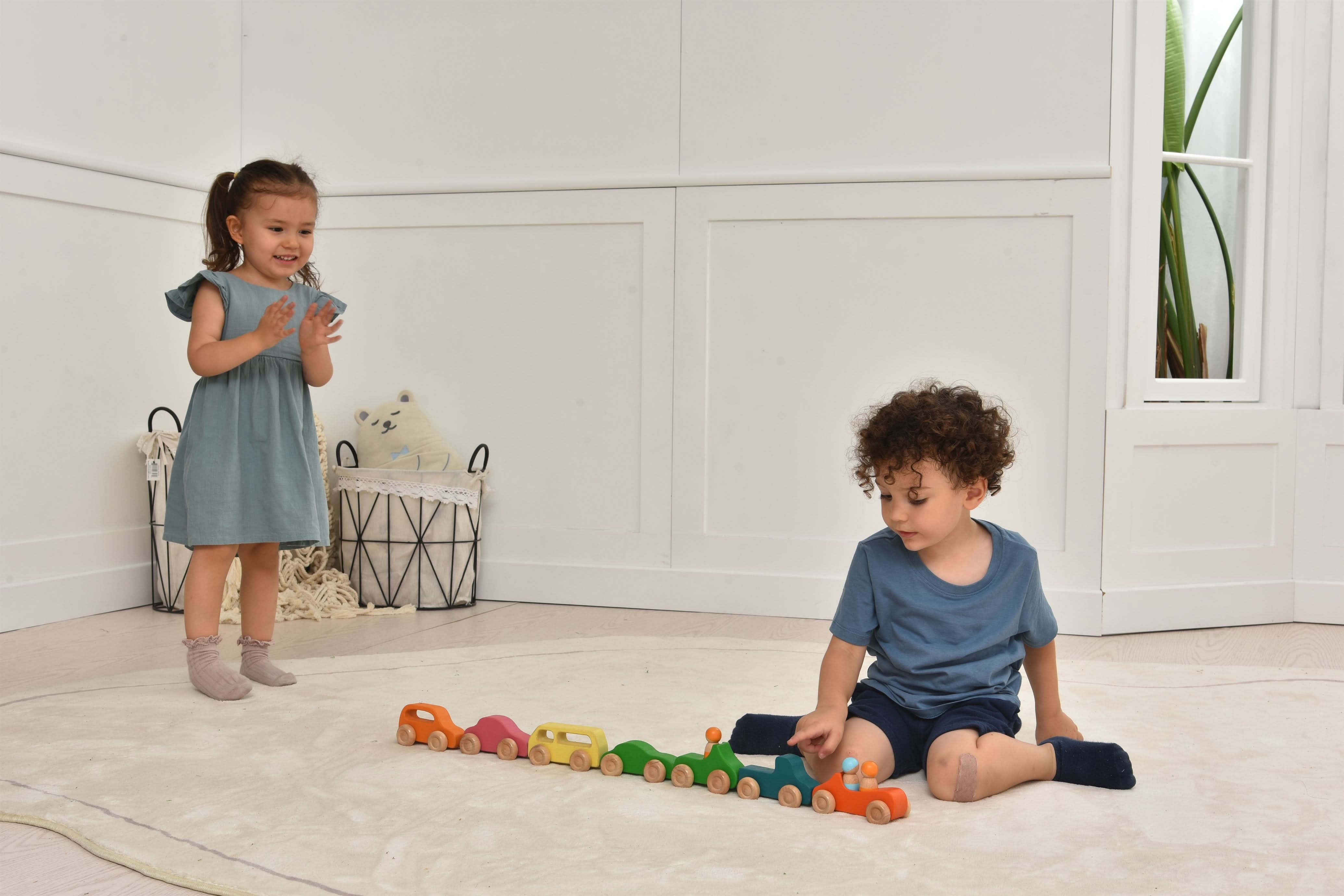Two children playing with toy cars on a light-colored floor.