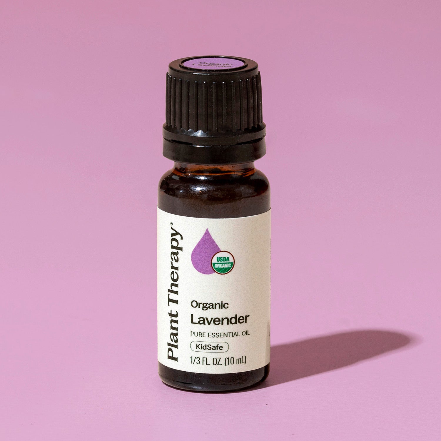 Bottle of Plant Therapy Organic Lavender essential oil on a pink background